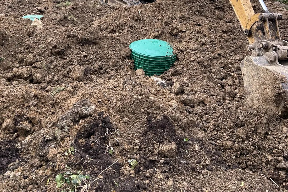 Main line install work — green riser and excavator bucket